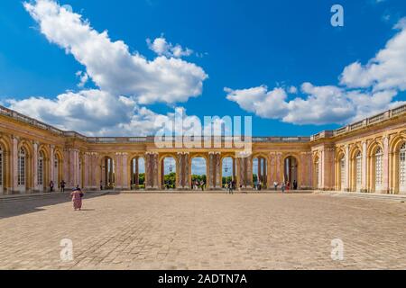 Bella vista panoramica di ciottoli cortile in pietra e il colonnato al riparo di collegamento tra le due ali della famosa Grand Trianon Palace in ... Foto Stock