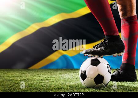 Chiudere le gambe della Tanzania football team player in rosso calzini, scarpe sul pallone da calcio al calcio di punizione o spot pena giocare sull'erba. Foto Stock