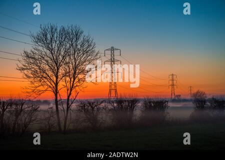 Tralicci di energia elettrica al tramonto sul livelli di Somerset dic 4 2019 Foto Stock