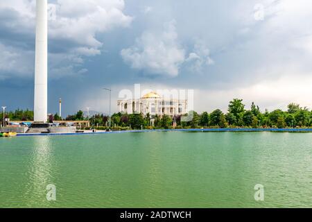 Dushanbe bandiera Polo pittoresco Parco Lago Vista del Palazzo delle Nazioni su un Nuvoloso Giorno di pioggia Foto Stock