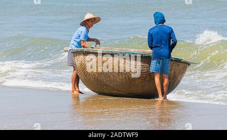Due pescatore vietnamita alaggio bamboo coracle barca da pesca al di fuori del mare Hoi An Vietnam Foto Stock