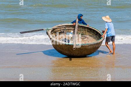 Due pescatore vietnamita alaggio bamboo coracle barca da pesca al di fuori del mare Hoi An Vietnam Foto Stock