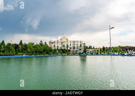 Dushanbe bandiera Polo pittoresco Parco Lago Vista del Palazzo delle Nazioni su un Nuvoloso Giorno di pioggia Foto Stock