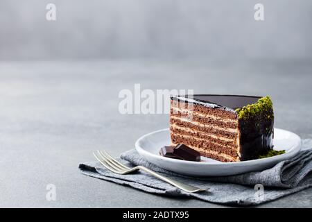 Torta al cioccolato su una piastra bianca. Grigio pietra dello sfondo. Spazio di copia Foto Stock