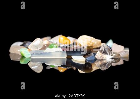 Varietà di colorati gemme ruvida, cristalli e minerali pietre di guarigione, sfondo nero con riflessi Foto Stock