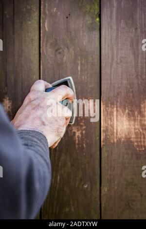 Do it yourself, closeup mano con una smerigliatrice elettrica su assi di legno o recinzione, copyspace Foto Stock