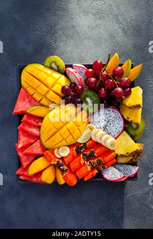 Frutti tropicali assortimento su una piastra. Sfondo di ardesia. Copia dello spazio. Vista superiore Foto Stock