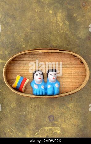 Due ingenui creta cifre seduto accanto al dipinto luminosamente striped cuscino di argilla Foto Stock