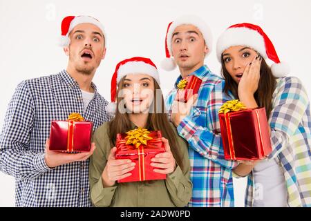 Giovani stupito la gente in cappelli di Babbo Natale azienda presenta Foto Stock