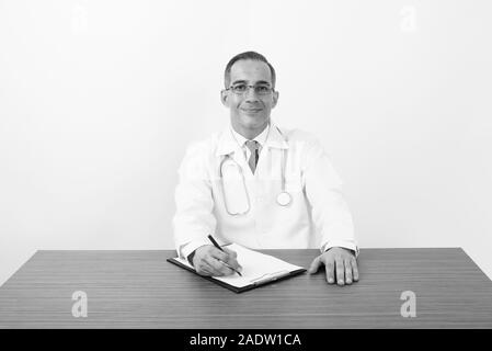 Maturo uomo persiano medico dietro la scrivania in bianco e nero Foto Stock