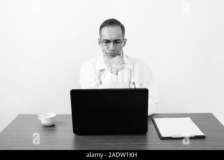 Maturo uomo persiano medico dietro la scrivania in bianco e nero Foto Stock