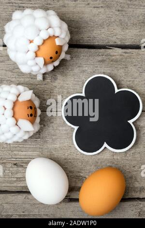 Il messaggio di saluto della scheda di pasqua con figure di pecora, uova e ardesia con copyspace, flatlay Foto Stock