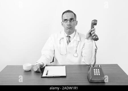 Maturo uomo persiano medico dietro la scrivania in bianco e nero Foto Stock