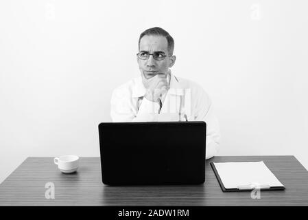 Maturo uomo persiano medico dietro la scrivania in bianco e nero Foto Stock