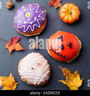 Le ciambelle con decorazione di Halloween, ciliegina sulla nero ardesia sfondo. Vista superiore Foto Stock