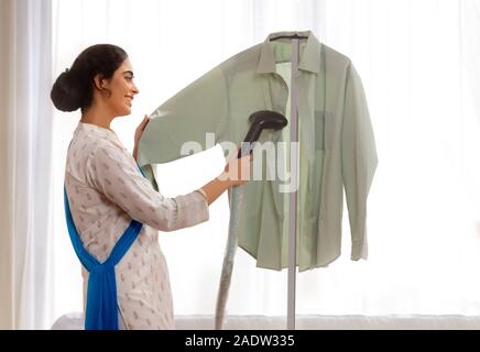Ritratto di una singola donna maglietta di stiratura a casa. Foto Stock