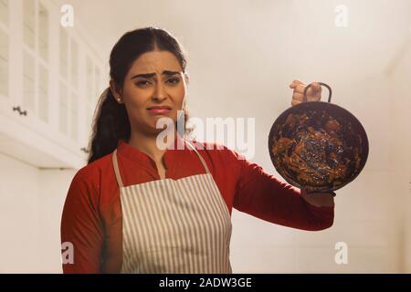 Ritratto di una donna che indossa un grembiule e tenere sporco arnese in mano. Foto Stock