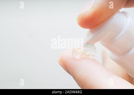 Le mani della donna l'applicazione di crema idratante per le sue dita la pelle da un tubo. bella ragazza la caduta di collagene Siero idratante in mano a casa Foto Stock