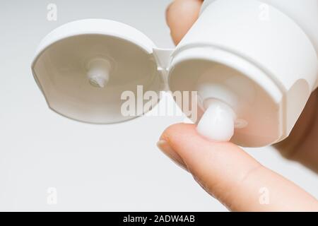 Le mani della donna l'applicazione di crema idratante per le sue dita la pelle da un tubo. bella ragazza la caduta di collagene Siero idratante in mano a casa Foto Stock