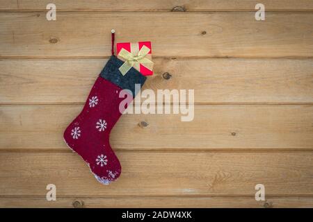 Calza di Natale pieno di doni appeso alla parete in legno Foto Stock