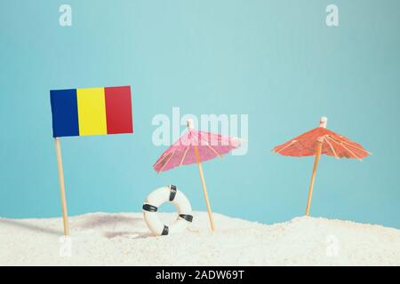 Miniatura Bandiera della Romania sulla spiaggia con ombrelloni colorati e salvagente. Concetto di viaggio, Tema estivo. Foto Stock