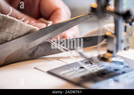 Mano femmina con una forbice è il taglio di un thread alla sua macchina da cucire Foto Stock