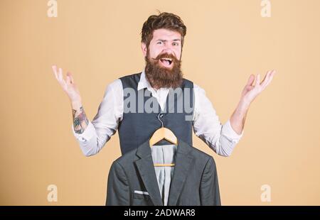 Infiammandosi per la moda. Aspetto emotivo del barbuto modello di moda. Designer di moda aiutando a scegliere tuta giacca. Stilista di moda azienda readymade cappotto formale. Foto Stock