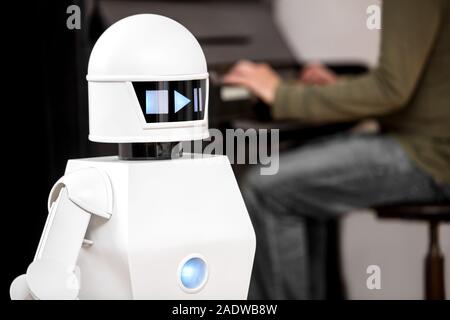 Intrattenimento musicale di robot di servizio è la riproduzione di file musicali mentre un uomo in background è la riproduzione di un pianoforte. Foto Stock