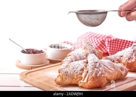 Ancora vita con croissant e ciotole di inceppamento. Femmina tenuta a mano un filtro e un pizzico di zucchero. Isolato su sfondo bianco. Foto Stock