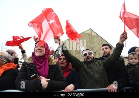 I membri del pubblico wave flags come presidente della Turchia Recep Tayyip Erdogan, arriva dal corteo di automobili per frequentare l'apertura ufficiale della nuova Cambridge Moschea centrale, in Cambridge. Foto Stock