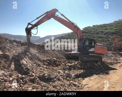 Hydrohammer è la frantumazione di rocce durante la guida su strada con opere di costruzione su terreni rocciosi. Macchinari pesanti a movimento di terra, scavo, le operazioni di scavo. Foto Stock