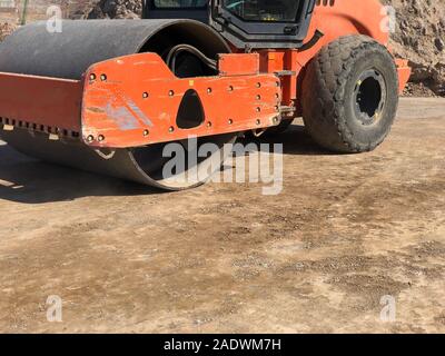 Rullo vibrante comprime il terreno di una superficie stradale durante la guida su strada con opere di costruzione. Movimento terra, scavi, scavando sui terreni rocciosi. Foto Stock