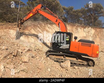 Hydrohammer è la frantumazione di rocce durante la guida su strada con opere di costruzione su terreni rocciosi. Macchinari pesanti a movimento di terra, scavo, le operazioni di scavo. Foto Stock