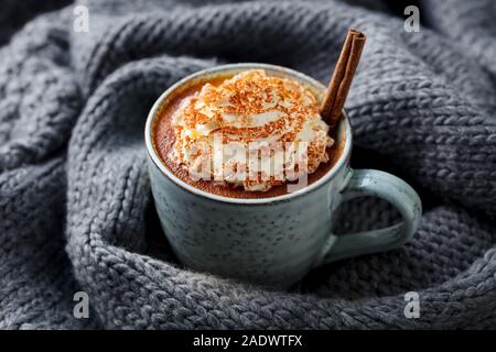 Latte macchiato di zucca con spezie panna montata. Grigio sfondo a maglia Foto Stock