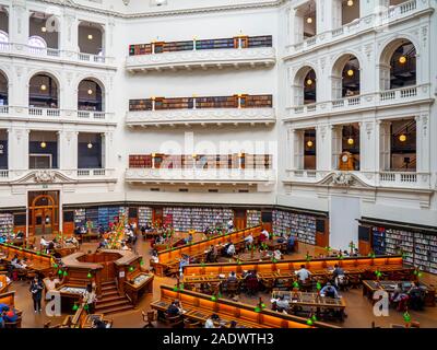 Tavoli in legno pieno di studenti che studiano in La Trobe Sala Lettura della Biblioteca di Stato di Melbourne Victoria Australia. Foto Stock