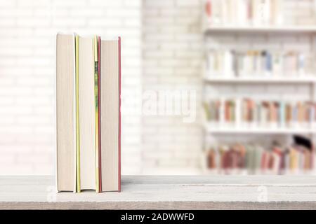 Tre libri su uno scaffale in una scuola università contro alcuni scaffali con riviste e altri libri di testo e di un bianco muro di mattoni. Copia vuota dello spazio. Foto Stock