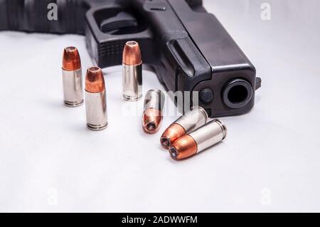 Sei 9mm punto cava proiettili nella parte anteriore di un nero 9mm pistola su sfondo bianco Foto Stock