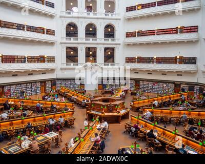 Tavoli in legno pieno di studenti che studiano in La Trobe Sala Lettura della Biblioteca di Stato di Melbourne Victoria Australia. Foto Stock