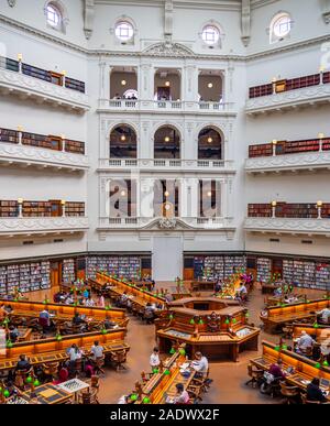 Tavoli in legno pieno di studenti che studiano in La Trobe Sala Lettura della Biblioteca di Stato di Melbourne Victoria Australia. Foto Stock