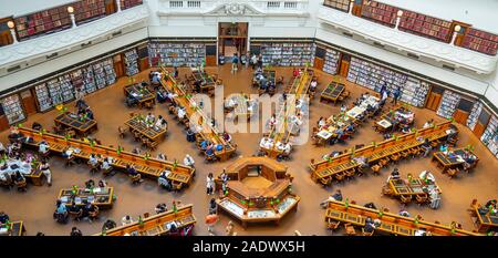 Tavoli in legno pieno di studenti che studiano in La Trobe Sala Lettura della Biblioteca di Stato di Melbourne Victoria Australia. Foto Stock