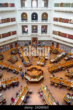 Tavoli in legno pieno di studenti che studiano in La Trobe Sala Lettura della Biblioteca di Stato di Melbourne Victoria Australia. Foto Stock