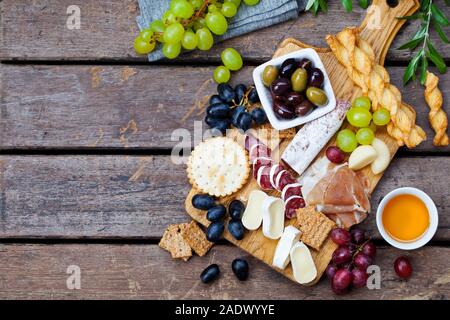 Formaggi e antipasti di carne sul tagliere di legno su sfondo. Copia dello spazio. Vista superiore Foto Stock