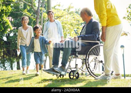 Felice tre generazioni della famiglia asiatica per godersi la natura in posizione di parcheggio Foto Stock