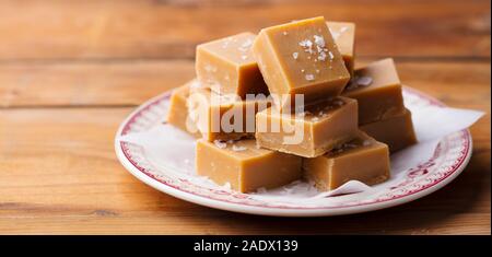 Caramel fudge caramelle su una piastra. Sfondo di legno. Close up Foto Stock