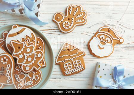 Piastra con biscotti di Natale, confezione regalo bianca su sfondo di legno, lo spazio per il testo. Vista superiore Foto Stock