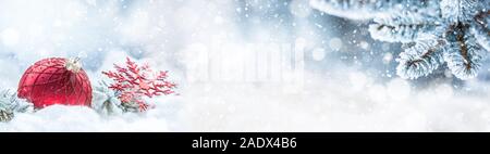 Red palla di Natale sulla neve con rami di abete. Merry Xmas concetto - Panoramica banner Foto Stock