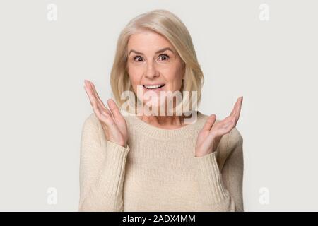 Colpo alla testa di sorpreso donna anziana che mostra un sincero stupore di emozioni Foto Stock