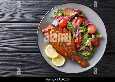 Il piatto principale è il pesce fritto servito con verdura fresca insalata di close-up in una piastra sul tavolo. parte superiore orizzontale vista da sopra Foto Stock