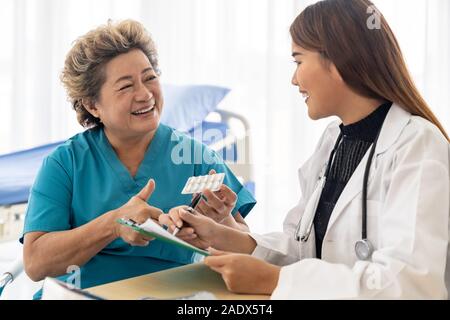 Asian medico donna parlando la prescrizione di pillole per il vecchio senior paziente anziano in sala esame della clinic hospital. Foto Stock