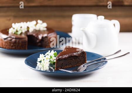 In casa sana Siberian dessert. Bird cherry la torta con la ganache al cioccolato servito con fiori di colore bianco su bianco tabella closeup Foto Stock